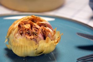 Cabezas enteras de ajo asado en una fuente de horno con mantequilla y romero