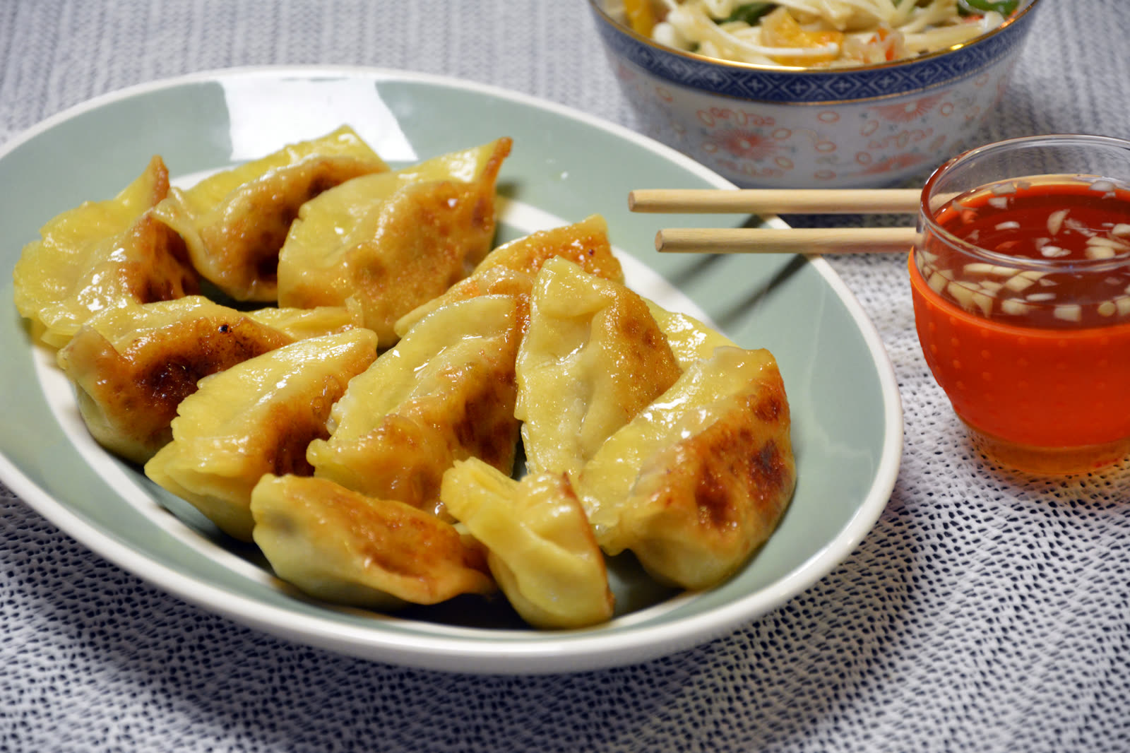 Gyozas caseras con la base dorada y crujiente hechas en sartén, servidas con salsa